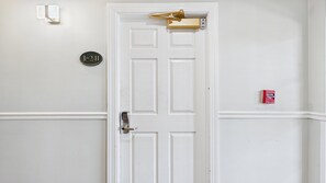 Una puerta blanca con cerradura electrónica, un buzón y un detector de incendios en la pared.