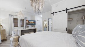 A bedroom with a large bed, a television, a wardrobe, and a chandelier.