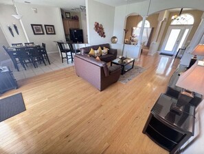 A spacious living area with a brown sofa, a coffee table, and a dining table with chairs.