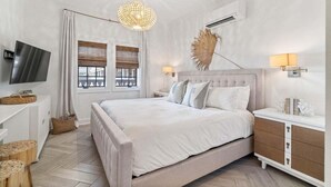 A bedroom with a large bed, a flat-screen TV, a bedside table, a lamp, and a decorative plant. - Summer Sand 30A 202-Coastal Studio-Sleeps 4 (Seacrest)