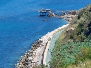 Une route côtière bordée d’une falaise rocheuse et d’un pont qui s’avance sur l’eau.