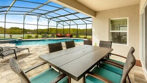 Un espacio al aire libre techado con piscina, asientos y vistas al paisaje.