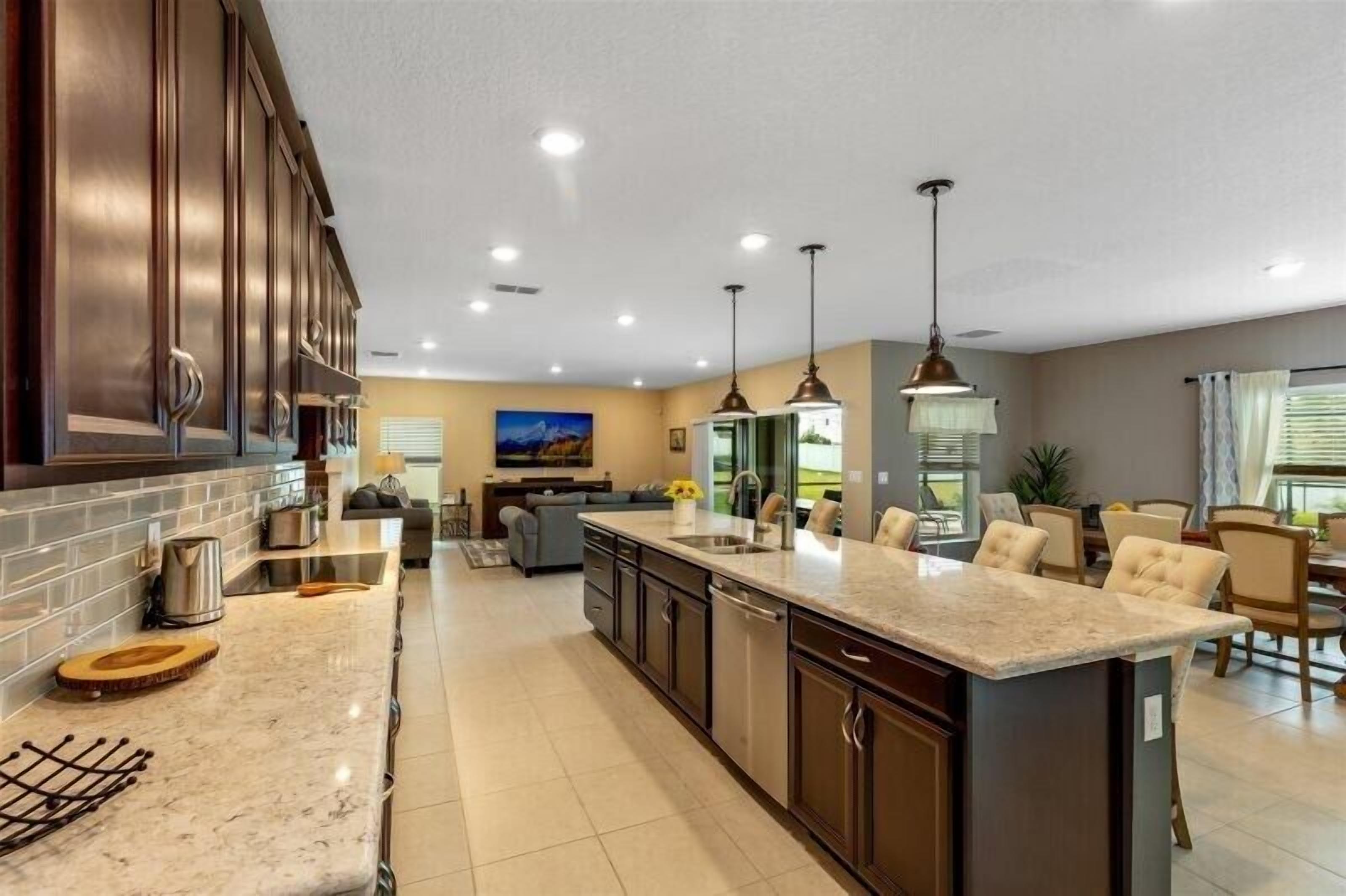 A modern kitchen with dark wood cabinets, a large island, and pendant lighting.
