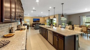 Una cocina moderna con gabinetes de madera oscura, una isla grande e iluminación colgante.