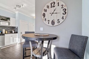 Un comedor con una mesa redonda, dos sillas y un reloj de pared grande.
