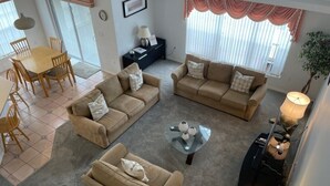 A spacious living area with two beige sofas, a glass coffee table, and a dining table with chairs. - Fabulous 4 Bed South Facing Lake View Near Disney (Kissimmee)
