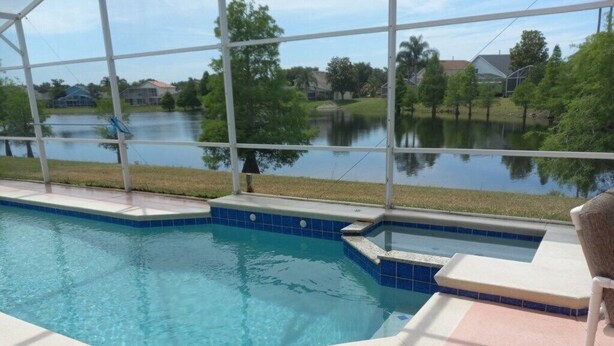A swimming pool with a view of a lake and houses in the background. - Fabulous 4 Bed South Facing Lake View Near Disney (Kissimmee)
