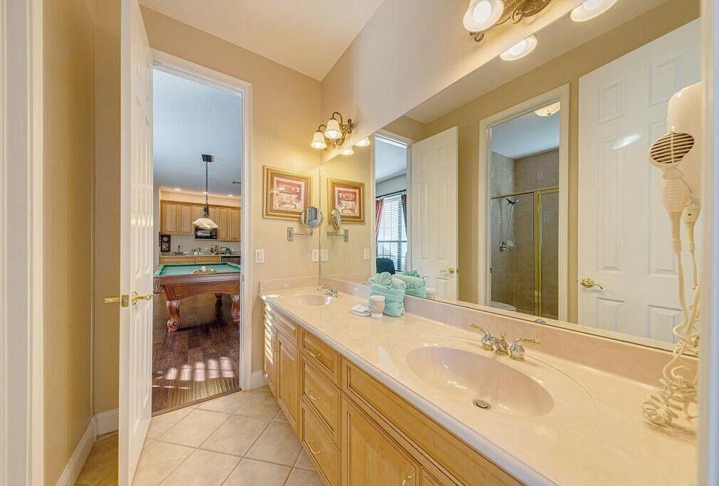 A bathroom with a large mirror, two sinks, and a vanity with drawers.