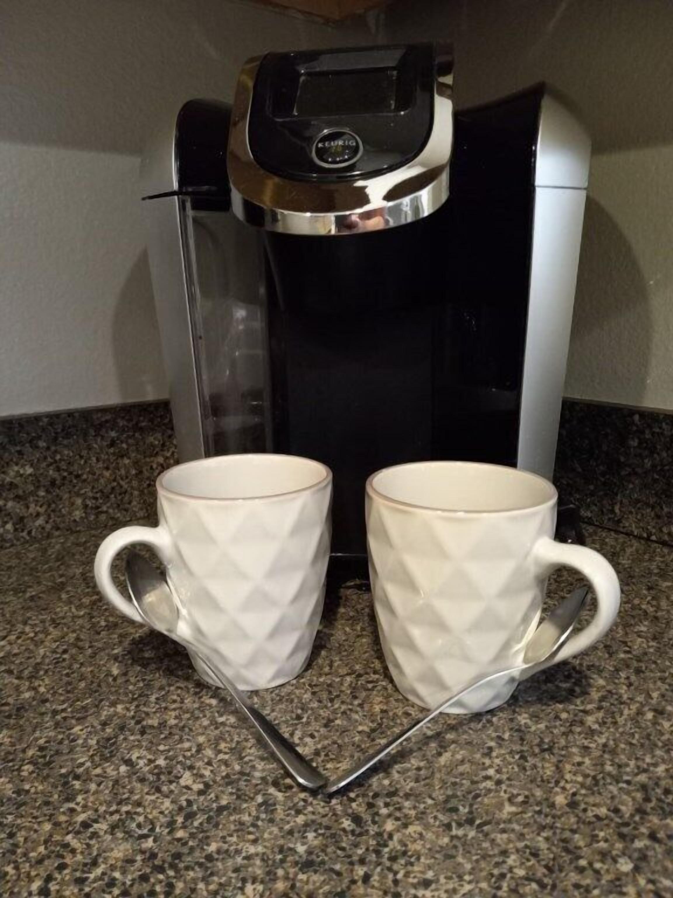 Eine Kaffeemaschine mit zwei weißen Tassen auf einer Granit-Arbeitsplatte.