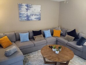 A modern living room with a sectional sofa, a round coffee table, and a painting on the wall.