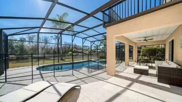 A covered outdoor area with a pool, seating, and a view of the surrounding landscape. - South Facing Villa With Water View Near Disney (Davenport)
