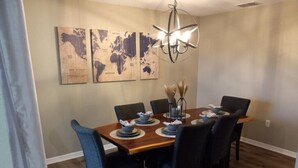 A dining area with a wooden table set for six, surrounded by chairs. There are three world maps on the wall above the table. - South Facing Villa With Water View Near Disney (Davenport)