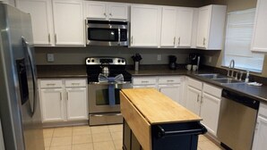 A modern kitchen with white cabinets, stainless steel appliances, and a wooden countertop. - South Facing Villa With Water View Near Disney (Davenport)