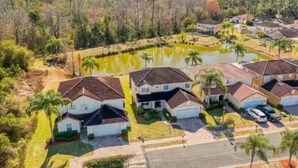A residential area with houses, a pond, and surrounding greenery. - South Facing Villa With Water View Near Disney (Davenport)