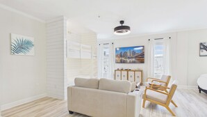 Ein modernes Wohnzimmer mit einer Couch, einem Holzstuhl, einem Schrank und einem Stadtbild an der Wand.