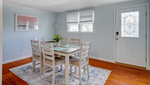 Un comedor con una mesa y sillas de madera, una planta en maceta y un tapete estampado.