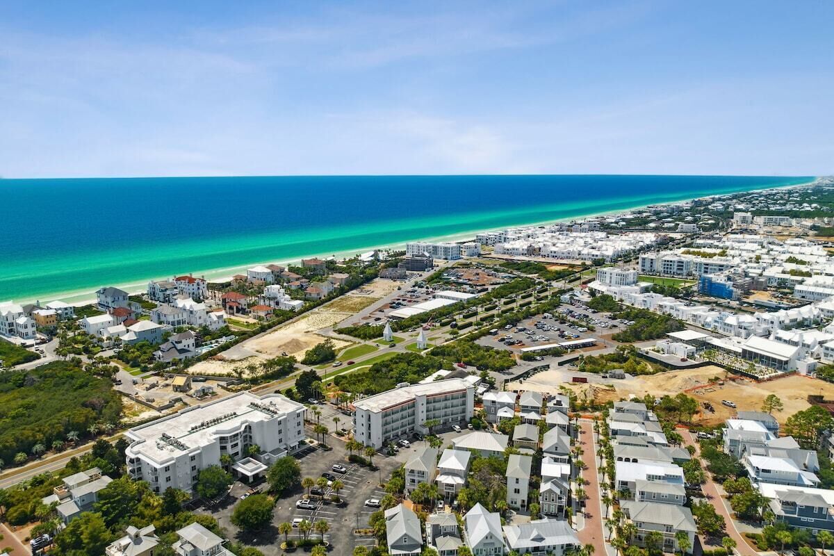 An aerial view of a coastal residential area with buildings, roads, and a beach.
