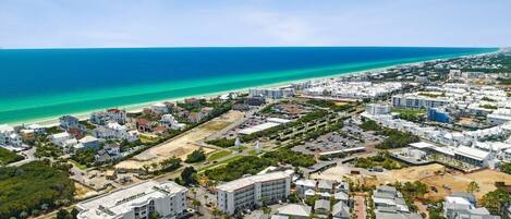 An aerial view of a coastal residential area with buildings, roads, and a beach.