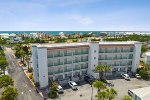 A multi-story building with a parking lot and a view of the ocean. - Dragana's Paradise 30A 410-Pool-Sleeps 2 (Seacrest Beach)