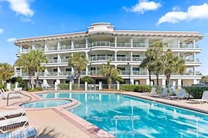 A multi-story hotel with a pool area, including lounge chairs and palm trees. - Dragana's Paradise 30A 410-Pool-Sleeps 2 (Seacrest Beach)