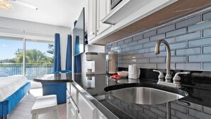 Una cocina moderna con encimera negra, pileta de acero inoxidable y vista al exterior.