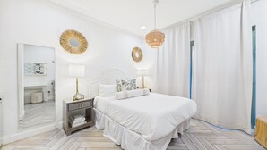 A bedroom with a large bed, bedside tables, a mirror, and decorative wall mirrors.