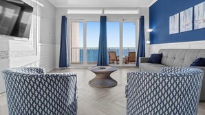 Un salon doté d’une grande fenêtre, d’une table basse ronde et de deux fauteuils à motifs.