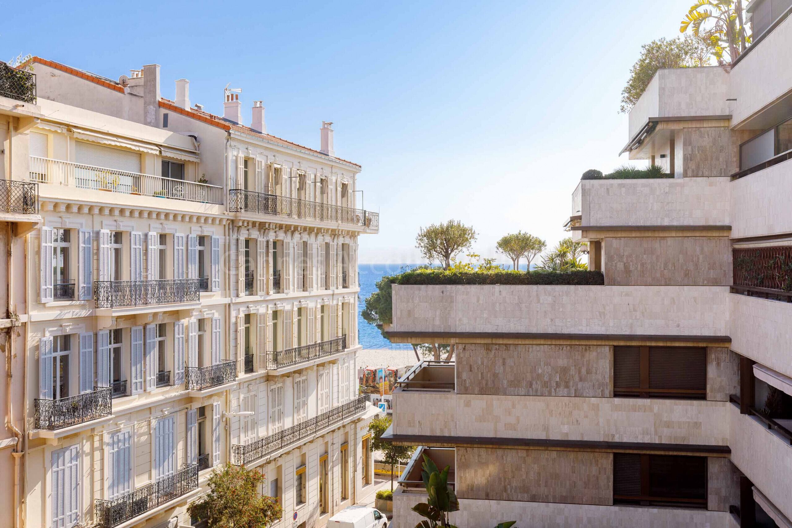 A multi-story building with balconies and a view of the sea.