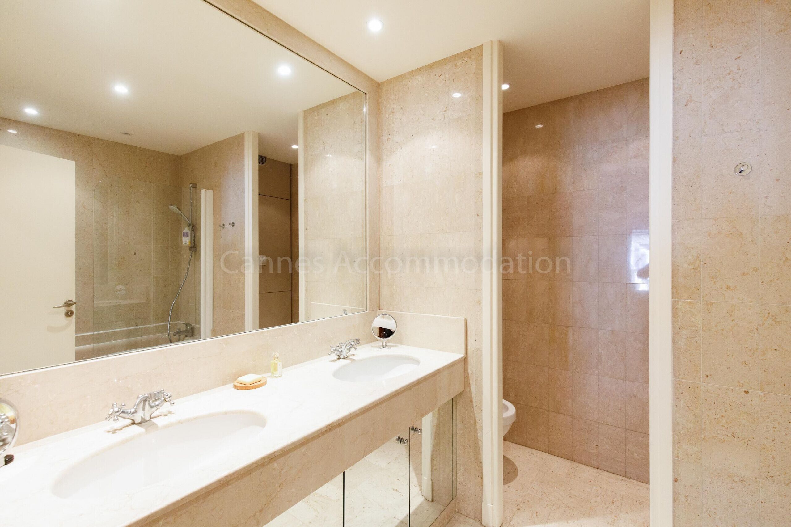 A modern bathroom with two sinks, a large mirror, and a shower area.