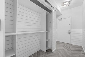 A hallway with white paneling and a herringbone-patterned floor.