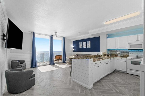 A modern kitchen with white cabinets, a granite countertop, and a built-in oven. - Queen of Tides 1907-Gulf Views-Sleeps 5 (Panama City Beach)