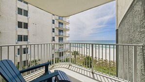 A balcony with a view of the beach, featuring a railing and a table.