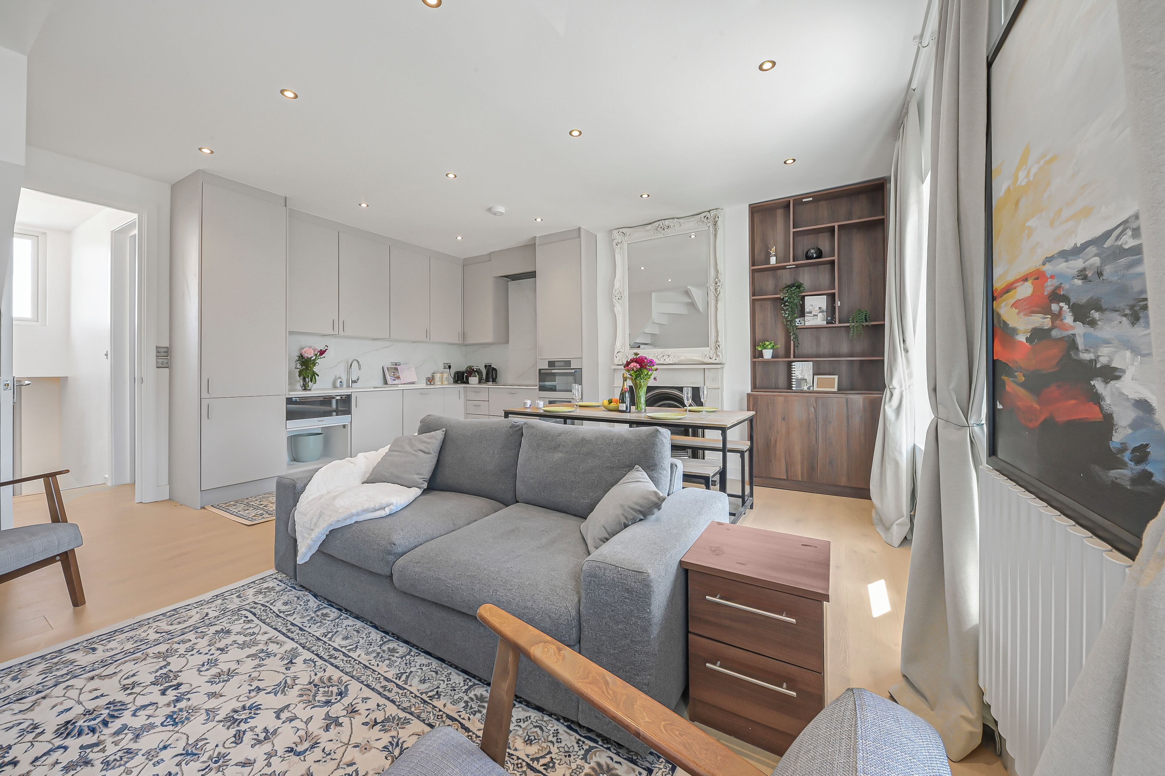 A modern living room with a grey sofa, wooden coffee table, and a patterned rug.