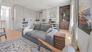 A modern living room with a grey sofa, wooden coffee table, and a patterned rug. - Oversize 3Bed 2bath Victorian Penthouse w/ AC in Maida Vale (London)