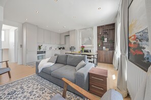 A modern living room with a grey sofa, wooden coffee table, and a patterned rug. - Oversize 3Bed 2bath Victorian Penthouse w/ AC in Maida Vale (London)