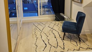 A modern bedroom with a large window, a glass table, a blue chair, and a patterned rug. - Oversize 3Bed 2bath Victorian Penthouse w/ AC in Maida Vale (London)
