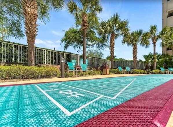 Una piscina con un letrero que indica 'OFF', rodeada de palmeras y sillas de descanso.