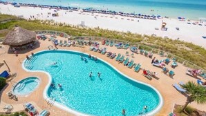 Una gran piscina con múltiples carriles, rodeada de tumbonas y una zona de playa.