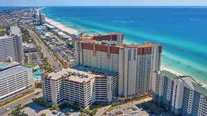 Un hotel moderno de gran altura con varios pisos, estacionamiento y vistas a la playa.