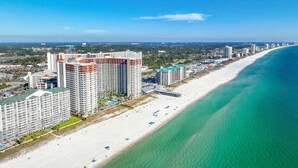 Un hotel costero con varios edificios altos, una playa y un cielo azul despejado.