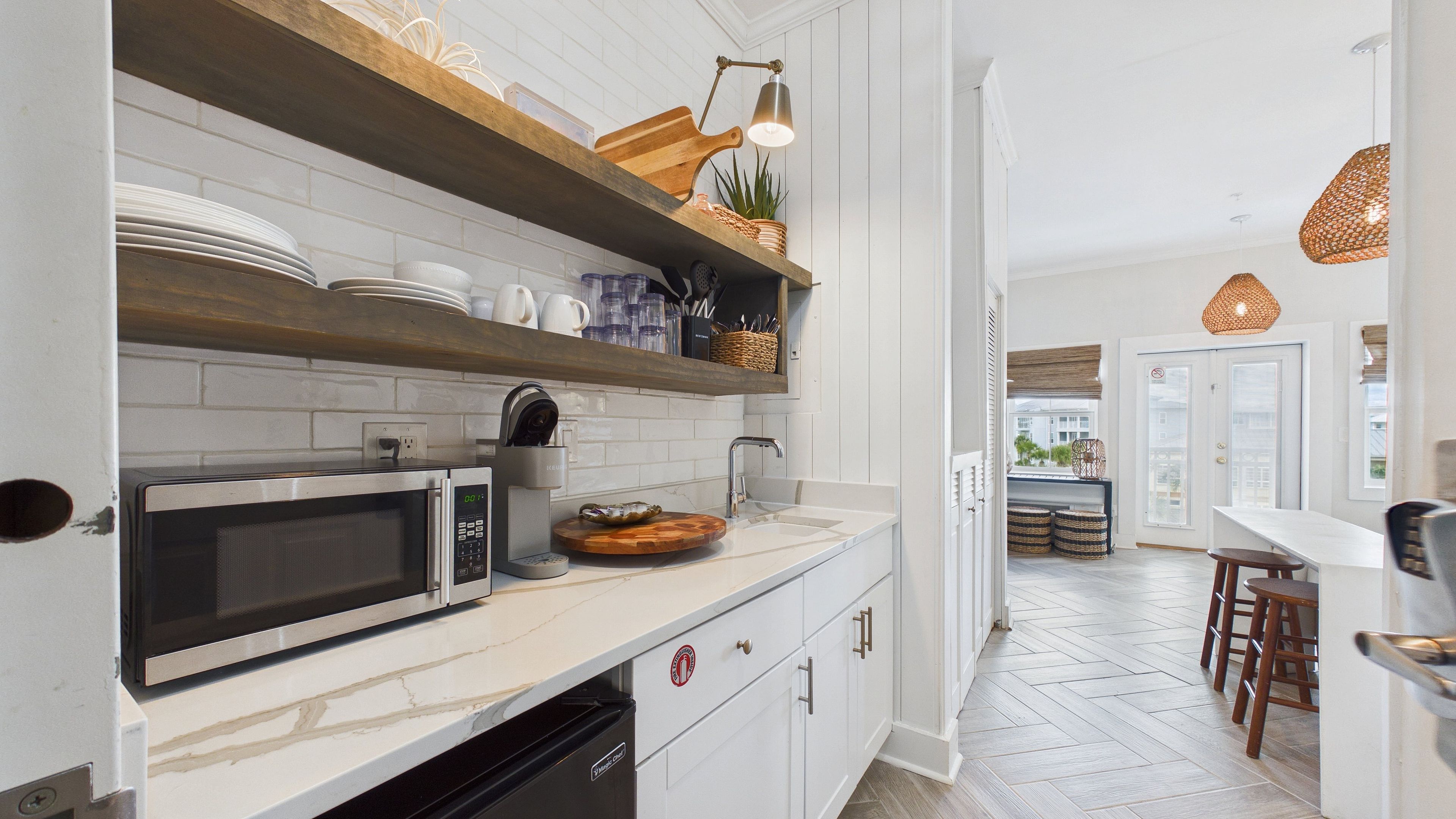A modern kitchen with a microwave, sink, and wooden shelves.