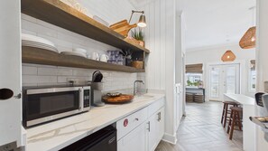 Une cuisine moderne équipée d’un four à micro-ondes, d’un évier et d’étagères en bois.