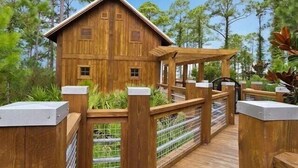 Une cabane en bois avec un porche et une terrasse entourée d’une clôture.