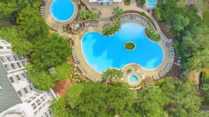 An aerial view of a resort with multiple swimming pools surrounded by lush greenery and palm trees. - Bay Watchin 3511- Beach Tram-Sleeps 6 (Miramar Beach)