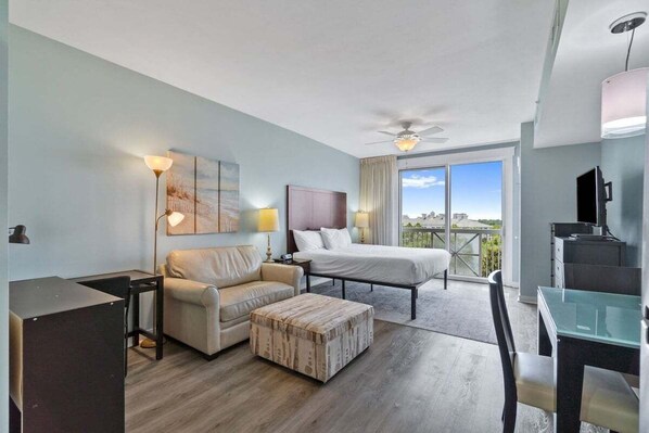 Una habitación de hotel moderna con cama, sofá y escritorio. Tiene un balcón con vistas.