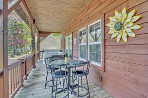 A wooden deck with a covered area, a table with chairs, and a decorative sunburst wall piece. - The Retreat at Rockridge ( HotTub )  (Pipestem)