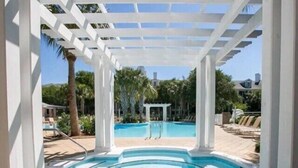 A pool area with a pergola structure, a small pool, and lounge chairs. - Beach Time 242–Near Beach–Sleeps 4 (Miramar Beach)