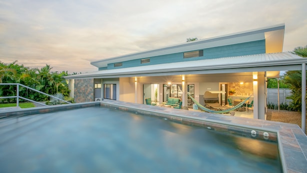 Una casa moderna con piscina, mobiliario exterior y zona de patio.