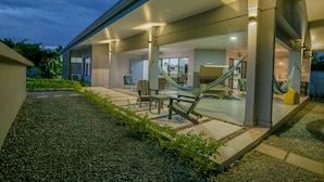 Un patio moderno al aire libre con una hamaca, asientos y vistas del interior.