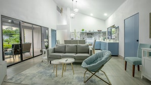 Una sala moderna con un sofá gris, un sillón azul y una mesita redonda.